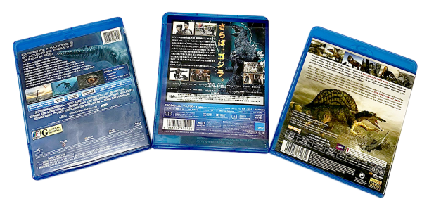 Three Dinosaur Blu-ray cases showing detailed back covers with images of prehistoric creatures and movie information.