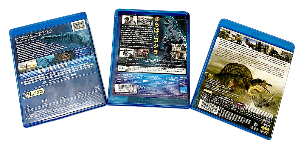 Three Dinosaur Blu-ray cases showing detailed back covers with images of prehistoric creatures and movie information.
