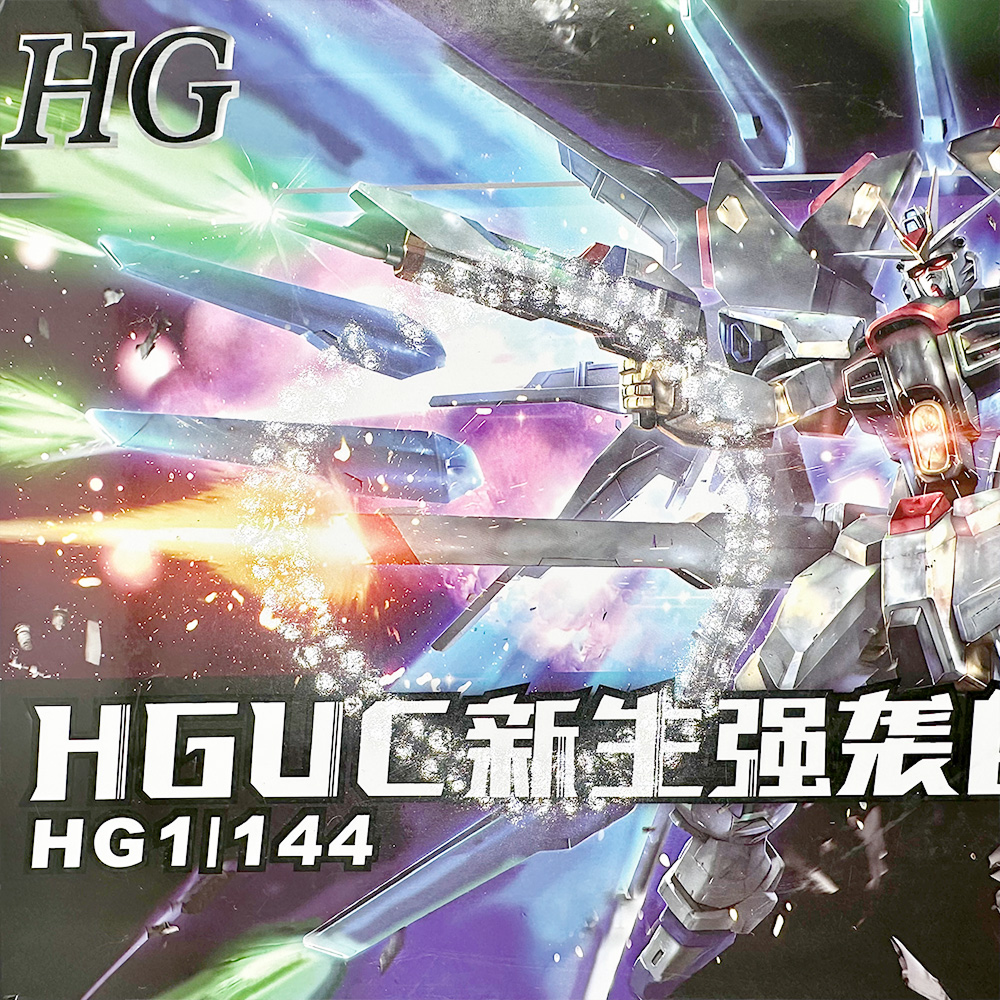 Strike Freedom Gundam figure box art with colorful beams and dynamic action pose, HG 1/144 scale.