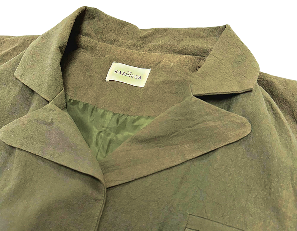 Close-up of Kashieca olive green dress collar and neckline showing fabric texture and brand label.