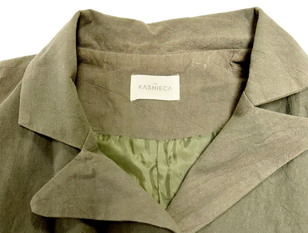 Close-up of the collar and label of a Kashieca olive green dress with an inner lining.