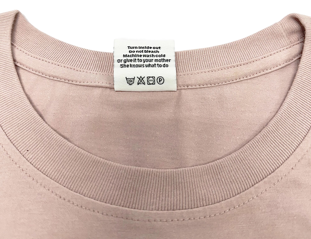 Close-up of the neck and care label of a FunTee Motor Atlanta Shirt in light pink.