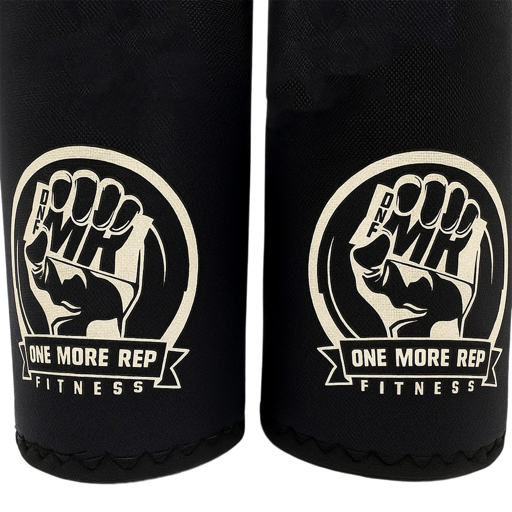 Close-up of One More Rep Fitness Kneepads featuring a fist logo and brand name on black fabric.