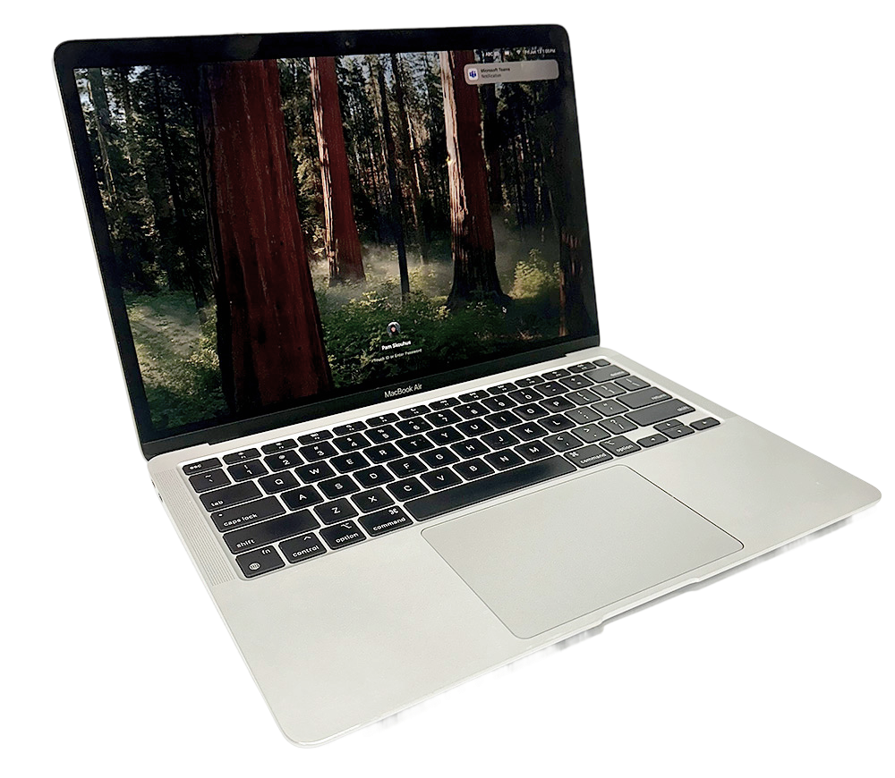 MacBook Air with a forest wallpaper displayed on screen, shown from the left side at an angle.