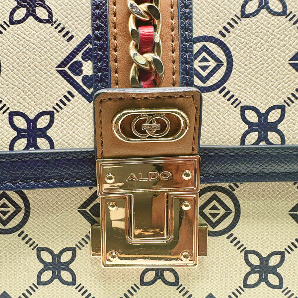 Close-up of Aldo Donelly handbag clasp with gold hardware and blue patterned fabric.