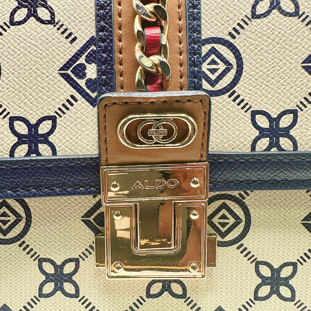 Close-up of Aldo Donelly handbag clasp with gold hardware and blue patterned fabric.