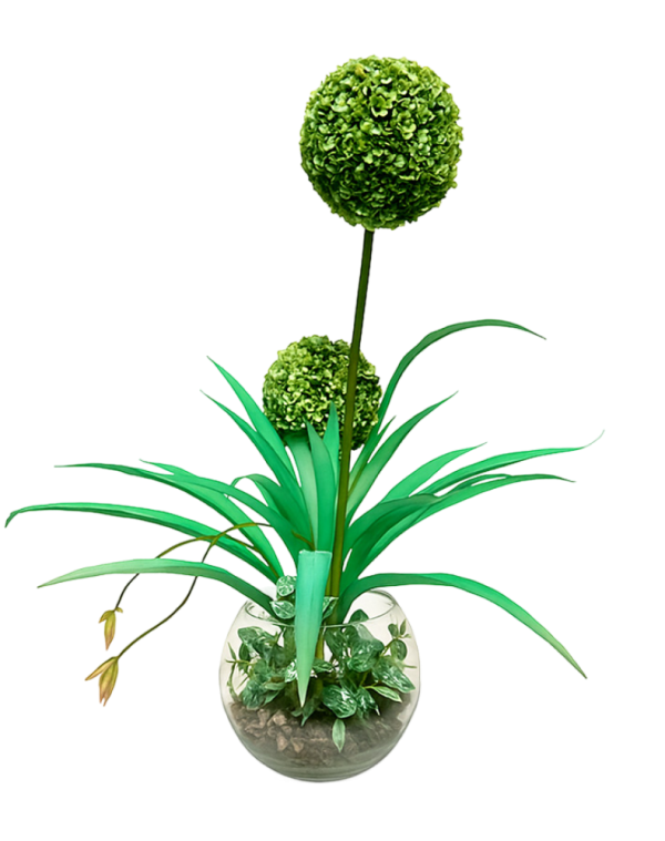 Faux topiary arrangement with two green orbs and long leaves in a clear glass vase.