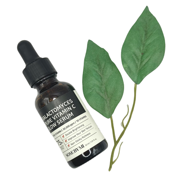 Some By Mi Vitamin C Serum bottle with dropper next to two green leaves on a white background.