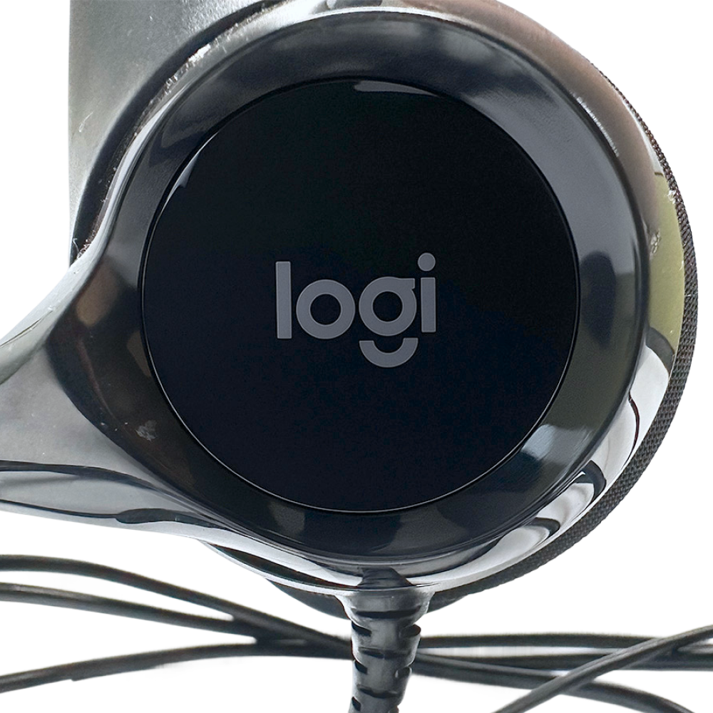 Close-up of Logitech H390 headset with mic showing logi logo on earcup and attached wired connection.
