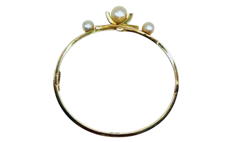 Gold bangle bracelet featuring three pearls arranged on top, displayed against a transparent background.