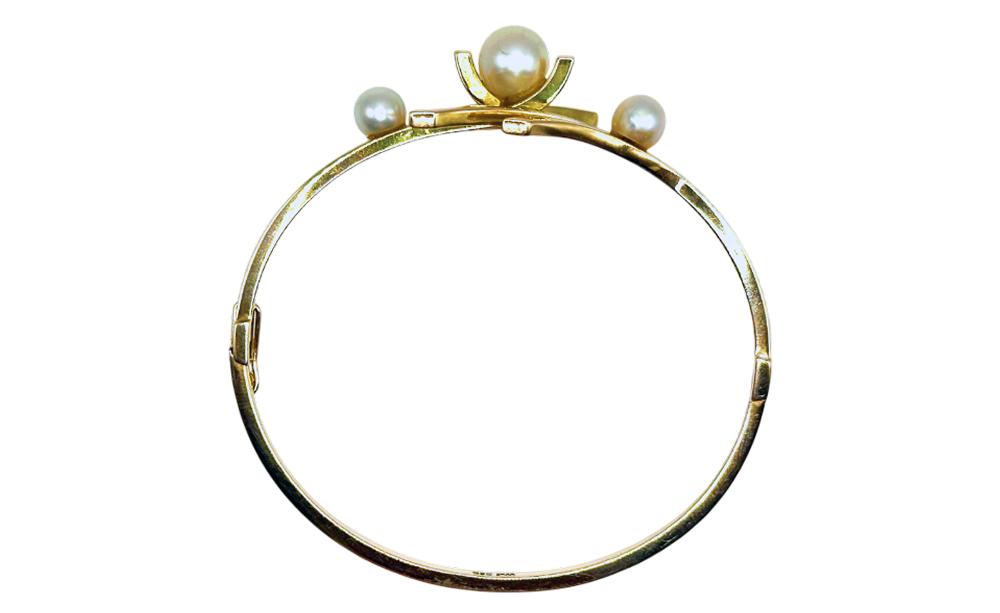 Gold bangle bracelet featuring three pearls arranged on top, displayed against a transparent background.