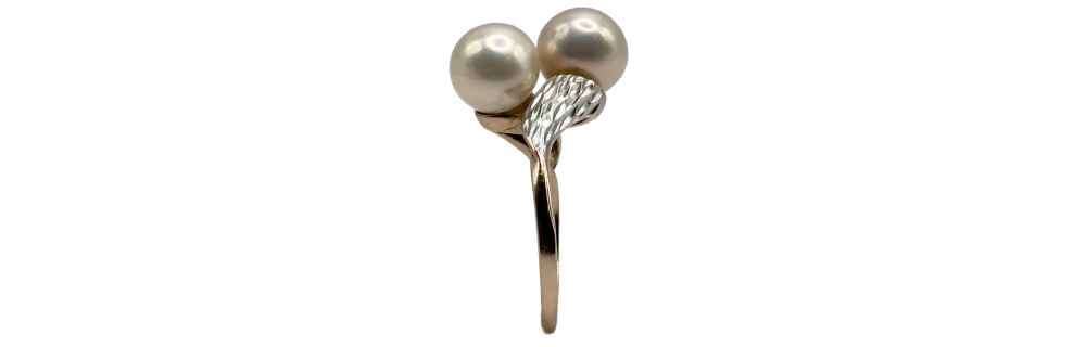 Gold-tone ring featuring two white pearls and a leaf-like accent on the band.