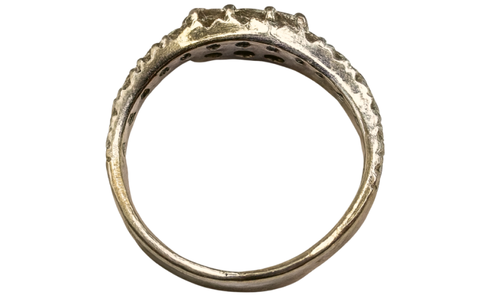 White gold diamond ring viewed from the side, showcasing band details and gemstone setting.