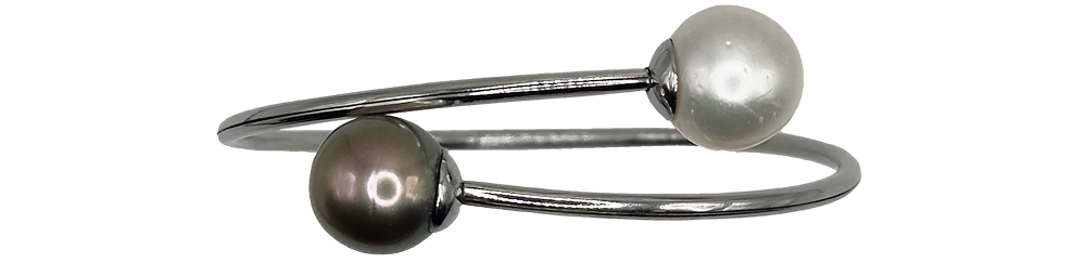 Silver bangle featuring one black pearl and one white pearl at each end, displayed on a product page.