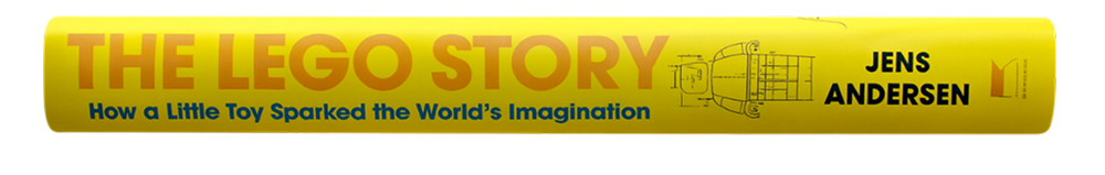 Book spine of "The LEGO Story" by Jens Andersen, yellow with blue and orange text and a LEGO brick illustration.