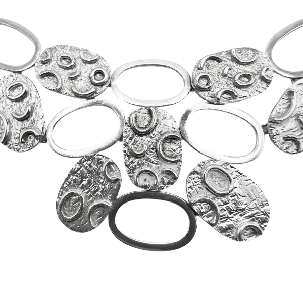 Close-up of a silver disc necklace featuring textured oval and circular pendants linked together.